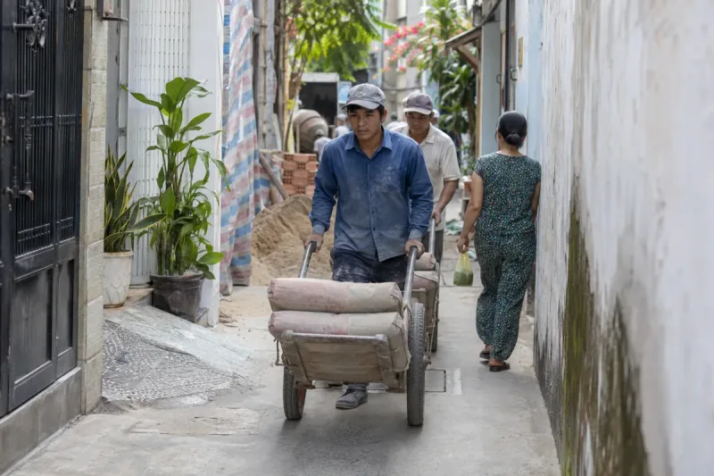 Công nhân vận chuyển vật tư qua hẻm nhỏ